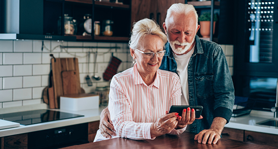 Frau und Mann in der Küche betrachten den Bildschirm eines Smartphones